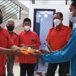 Ketua DPC PDI Perjuangan Kabupaten Kediri Murdi Hantoro saat menyerahkan potongan tumpeng kepada Agus Setiawan, perwakilan tukang. foto: MUJI HARJITA/ BANGSAONLINE