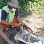 Samirin, saat memecah batu kali untuk dijadikan batu coral untuk bahan cor bangunan. (foto: MUJI HARJITA/ BANGSAONLINE)