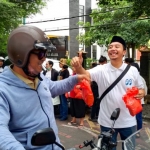 Anggota DPRD Gresik, Dimas Setyo Wicaksono membagikan takjil kepada pengguna jalan di depan kantor Kemenag Gresik. FOTO: SYUHUD/BANGSAONLINE.