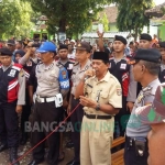 Kades Kandangan Sukiran saat menemui pendemo dengan dikawal polisi. foto: ZAINAL ABIDIN/ BANGSAONLINE