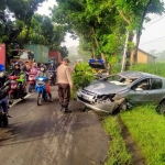 Petugas Polsek Gurah saat mengevakuasi mobil yang menabrak pohon di Jalan Raya Kediri-Pare. Foto: Ist