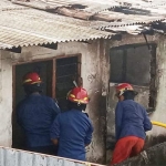 Petugas Damkar melakukan pembasahan di kamar-kamar kos yang terbakar.