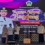 Bupati Gus Yani menyerahkan trofi kepada pemenang lelang bandeng. foto: SYUHUD/ BANGSAONLINE