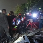Petugas saat mengevakuasi Honda Brio yang mengalami kecelakaan di perlintasan kereta api Jalan Manunggal Kebonsari, Surabaya.