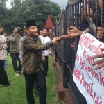 Plt Bupati trenggalek saat menyalami para pendemo di depan pendopo Trenggalek. Foto: HERMAN S/BANGSAONLINE