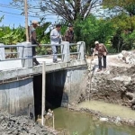 Kades Sekargadung Sumarto bersama tim pelaksana saat meninjau dam pintu air. Foto: Ist