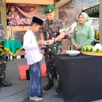 Komandan Kodim 0819 Pasuruan, Letkol Inf Boga Bramiko, didampingi Ketua Ibu Persit Ny. Vita Boga Bramiko saat memberikan potongan tumpeng ke salah satu peserta khitan.