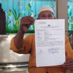 Sunarto (67) warga Veteran, Kecamatan Pademawu, Pamekasan, saat menunjukkan bukti laporannya ke polisi.