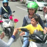 Ibu-ibu pengendara motor saat diberi setangki bunga mawar oleh para mahasiswa.