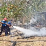 Petugas Damkar melakukan pembasahan di lokasi kebakaran.