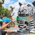 Mbah Suwari dan patung macan putih hasil karyanya. Foto: MUJI HARJITA/BANGSAONLINE