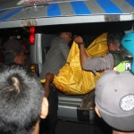 Petugas bersama pengguna jalan mengevakuasi jenazah korban.