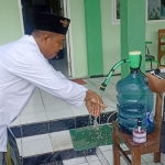 Salah satu guru memanfaatkan tempat cuci tangan otomatis karya siswa SMK Darul Muqomah.