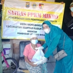 Istri Kades Morobakung Kecamatan Manyar Ny. Shohifatin Muhammad Askur Farid saat memberikan bantuan kepada warga terdampak PPKM Mikro. Foto: SYUHUD/BANGSAONLINE.com