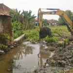 Alat berat melakukan normalisasi saluran pembuangan yang mengalami pendangkalan.