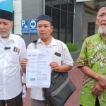 Gihari (tengah) sedang memegang surat outusan didampingi kuasa hukumnya. Foto: YUDI A/BANGSAONLINE