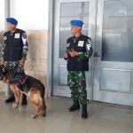 Para petugas keamanan yang sedang berjaga berikut anjing pelacak (K9).