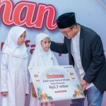 Direktur Keuangan dan Strategi Bank DKI, Romy Wijayanto, saat menyalurkan santunan secara simbolis kepada salah satu anak yatim.