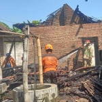 Petugas saat mengevakuasi rumah yang terbakar di Jombang.