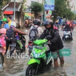 Para pengendara melewati jalan yang terendam di Morowudi Kecamatan Cerme. foto: SYUHUD/ BANGSAONLINE