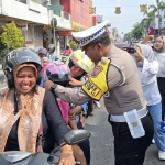 Petugas dari Satlantas Polres Mojokerto Kota saat memasangkan helm kepada pengendara.