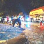 BIKIN MASALAH: Petugas Polsek Mojosari mengawasi warga membersihkan tumpahan limbah bubur kertas di jalan raya. foto: gunadhi/BANGSAONLINE
