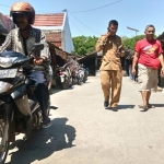 Dengan menaiki sepeda motor, salah satu warga sedang menikmati jalan pasar yang baru dicor dan diaspal.