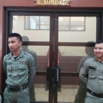 Dua petugas Satpol disiagakan di pintu masuk ruang Komisi I DPRD Gresik. foto: SYUHUD/ BANGSAONLINE