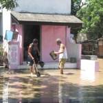 TERGENANG – Warga perumahan di kawasan Kota Madiun membersihkan lingkungan rumahnya yang tergenang air banjir, Rabu (25/3). Foto: hendro/BANGSAONLINE