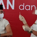 Suntikan vaksin Covid-19 pertama di Bangkalan yang dilakukan oleh Kepala Dinas Kesehatan Kabupaten Bangkalan Sudiyo, S.Kep.Ns., M.M., terhadap Bupati Bangkalan R. Abdul Latif Imron Amin. (foto: ist)