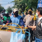 Kapolres Kediri Kota AKBP Wahyudi dan Sunardi dari HDCI Jawa Timur saat membagikan paket sembako kepada abang becak yang melintas di depan Mapolres Kediri Kota. foto: MUJI HARJITA/ BANGSAONLINE