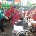 Indah Kurnia ketika memberikan kursi roda ke warga di sela sosialisasi dengan OJK di Surabaya. Foto: Ist