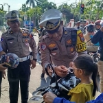 Petugas saat membagikan helm ke pengendara dalam Operasi Patuh Semeru 2025 di Jombang.