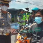 Kasat Lantas Polres Gresik AKP Anggi Saputro Ibrohim saat bagi-bagi masker di jalan Manyar. foto: SYUHUD/ BANGSAONLINE