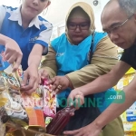 Petugas membuka parsel yang sudah dikemas untuk mengecek kondisi barang. foto: AKINA/ BANGSAONLINE