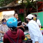 Ketua LSM FPSR Aris Gunawan saat bagi-bagi masker kepada para pengunjung pasar Karangandong, Driyorejo, yang masih berjubel di saat PSBB. foto: SYUHUD/ BANGSAONLINE