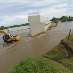 Tampak aliran air sungai yang jebol menggenangi area proyek jalan tol. 