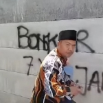 Anggota DPRD Kabupaten Malang, Zia Ulhaq, saat menuliskan tanda pembongkaran tembok.
