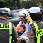 Petugas dari Satlantas Polres Gresik saat menyosialisasikan keselamatan berkendara kepada pengguna jalan sembari membagikan cokelat. Foto: Ist