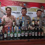 Kapolsek Kota Kediri, Kompol Mustakim (tengah), bersama jajaran saat menunjukkan barang bukti berupa ratusan botol miras berbagai merek. Foto: Ist