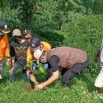 Plt. Kepala Pelaksana BPBD Kabupaten Kediri Slamet Turmudi didampingi relawan saat ikut menanam pohon di area Waduk Siman, Kecamatan Kepung, Minggu (7/3/2021). (foto: MUJI HARJITA/BANGSAONLINE)