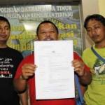 Wawan Sugiarto (tengah) wartawan TV One menunjukkan surat laporannya. foto: bruriy suarasurabaya