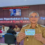 Kepala Dispendukcapil Kota Kediri, Marsudi Nugroho saat memegang e-KTP. (Ist).