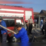 Petugas PMK memadamkan api di mobil kijang milik Suyatno yang terbakar.