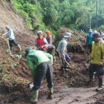 Petugas dari BPBD Kota Batu bersama masyarakat saat berjibaku membersihkan bekas longsor di jalan Pura Giri Arjuno, Dusun Junggo, Desa Tulungrejo, Kecamatan Bumiaji. 