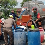 Babinsa Koramil 0817/11 Duduksampeyan, Sertu Agung Rudianto, saat membantu BPBD Gresik mendistribusikan air bersih di Desa Bendungan.