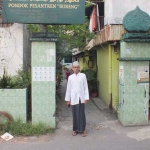 KH Mas Abdul Hamid Sya’roni, biasa disapa Abah Hamid, Pengasuh Ponpes Bureng, berpose di depan akses masuk ke pesantren dari Jalan Ketintang. foto: YUDI ARIANTO/ BANGSAONLINE
