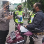 Kapolres Gresik AKBP Arief Fitrianto sedang memberikan penjelasan PPKM Darurat kepada salah seorang pengguna jalan saat operasi yustisi. foto: SYUHUD/ BANGSAONLINE