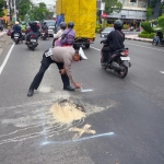 Petugas Satlantas Polres Blitar memberikan penanda pada jalan yang rusak menggunakan cat semprot berwarna putih.