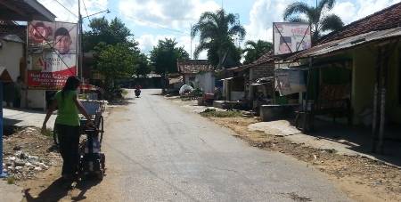 Baleho salah satu kandidat bupati yang akan maju di pilkada mendatang berdiri kokoh di pemukian warga. (Faisal/BANGSAONLINE)